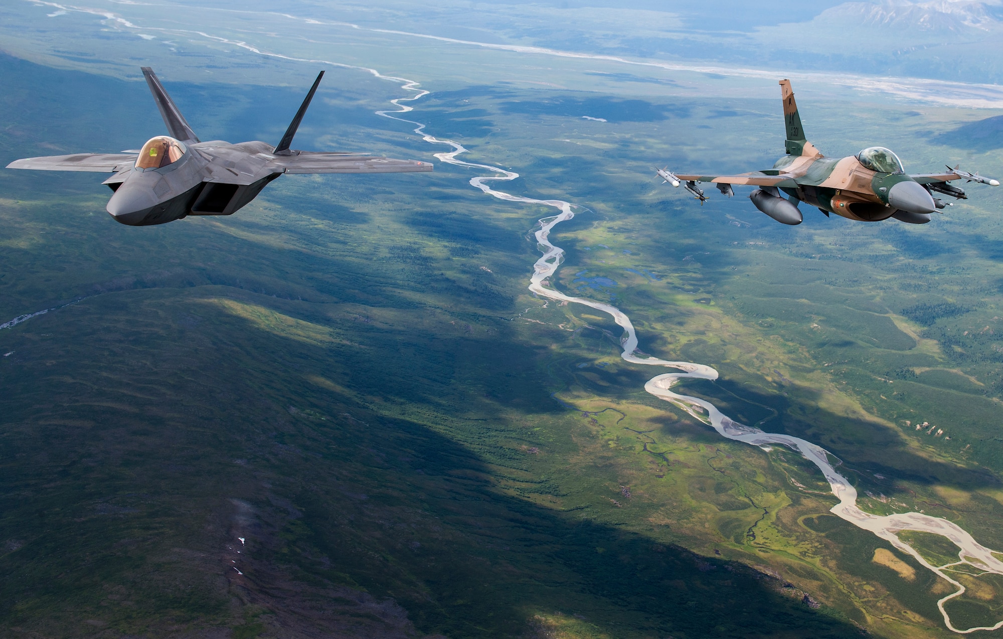 A U.S. Air Force F-22 Raptor from Joint Base Elmendorf-Richardson and an F-16 Fighting Falcon from Eielson Air Force Base fly in formation over the Joint Pacific Alaska Range Complex, July 18, 2019.