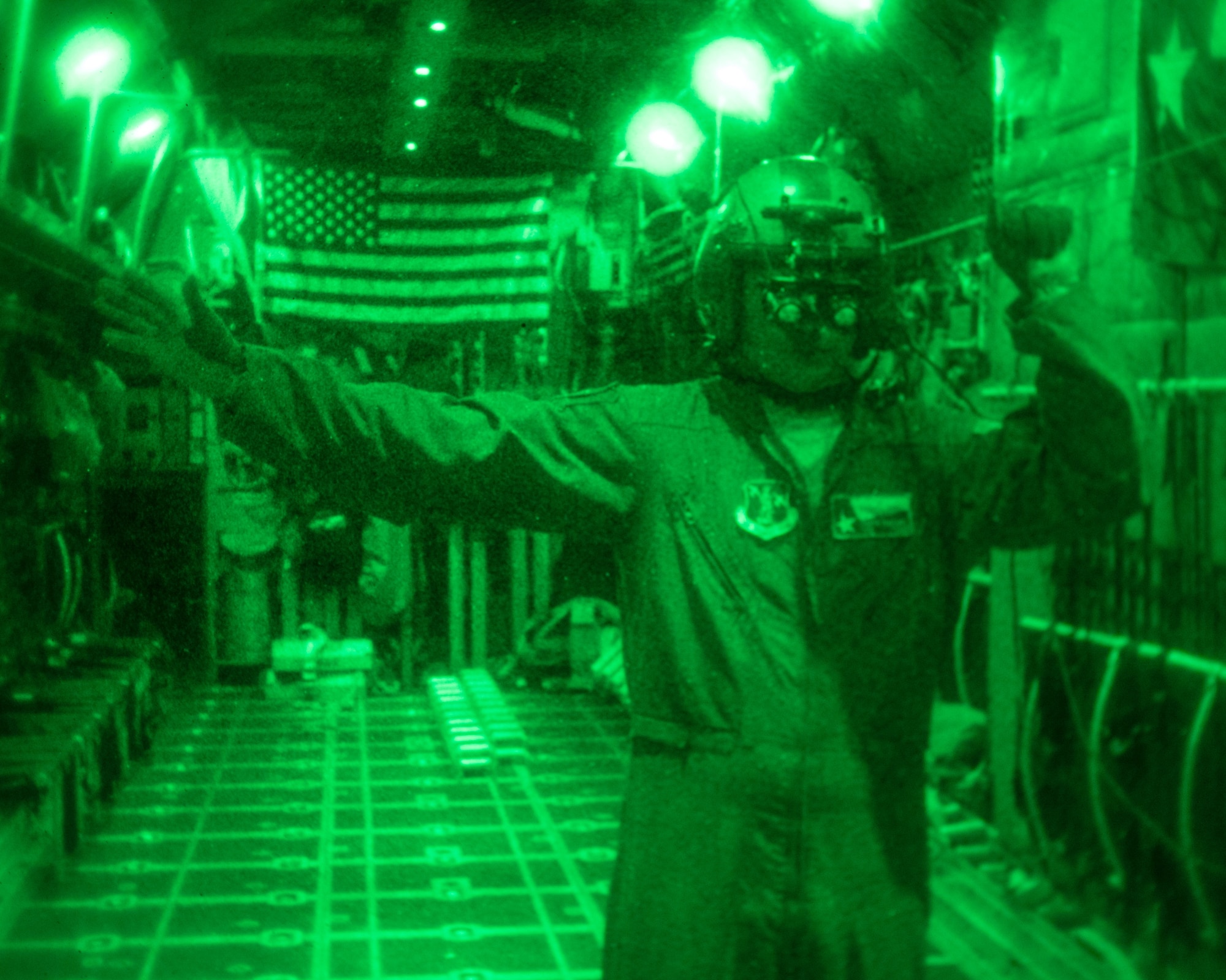 An Airman provides direction via hand gestures to assist loading cargo to a C-130.