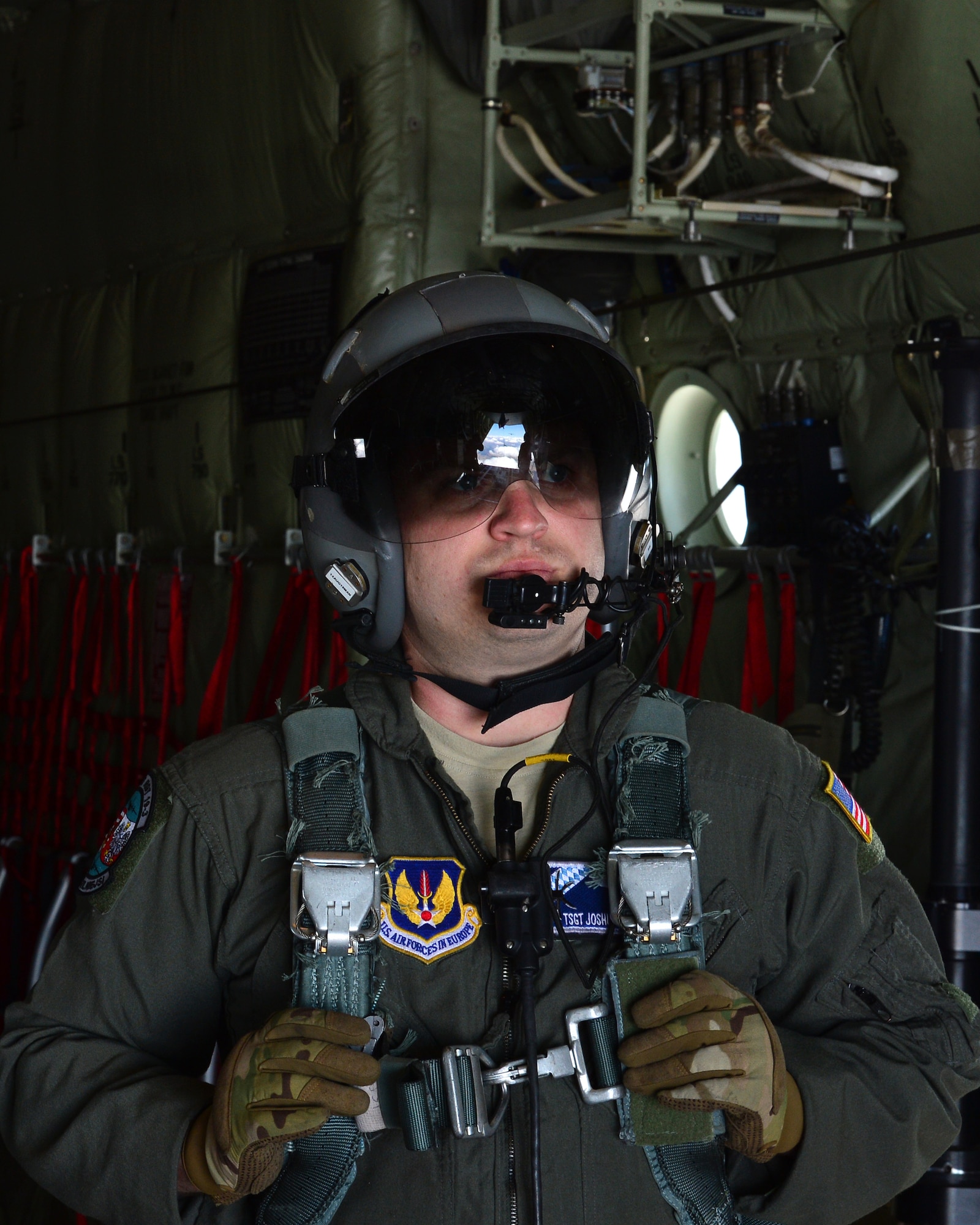 U.S. Air Force Tech. Sgt. Joshua Schickedanz, 37th Airlift Squadron loadmaster, looks out of a C-130J Super Hercules cargo door during a flight over Powidz Air Base, Poland, July 18, 2019. As a loadmaster, Schickedaz assisted in the proper configuration of equipment, pallets, and personnel loaded in C-130J Super Hercules for safe operation. (U.S. Air Force photo by Staff Sgt. Jimmie D. Pike)