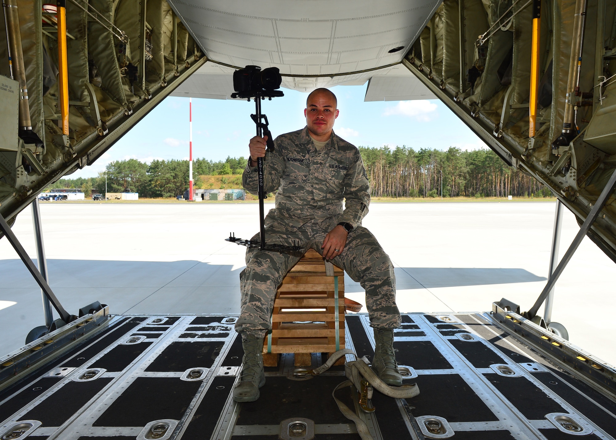 U.S. Air Force Staff Sgt. Devin Nothstine, 86th Airlift Wing Public Affairs broadcast journalist, shows off his equipment prior to takeoff from Powidz Air Base, Poland, July 11, 2019. As a member of public affairs and a broadcaster, Nothstine was responsible for documenting operations, creating and distributing videos, and working with media outlets to highlight U.S. and Polish efforts during Aviation Rotation 19-3. (U.S. Air Force photo by Staff Sgt. Jimmie D. Pike)