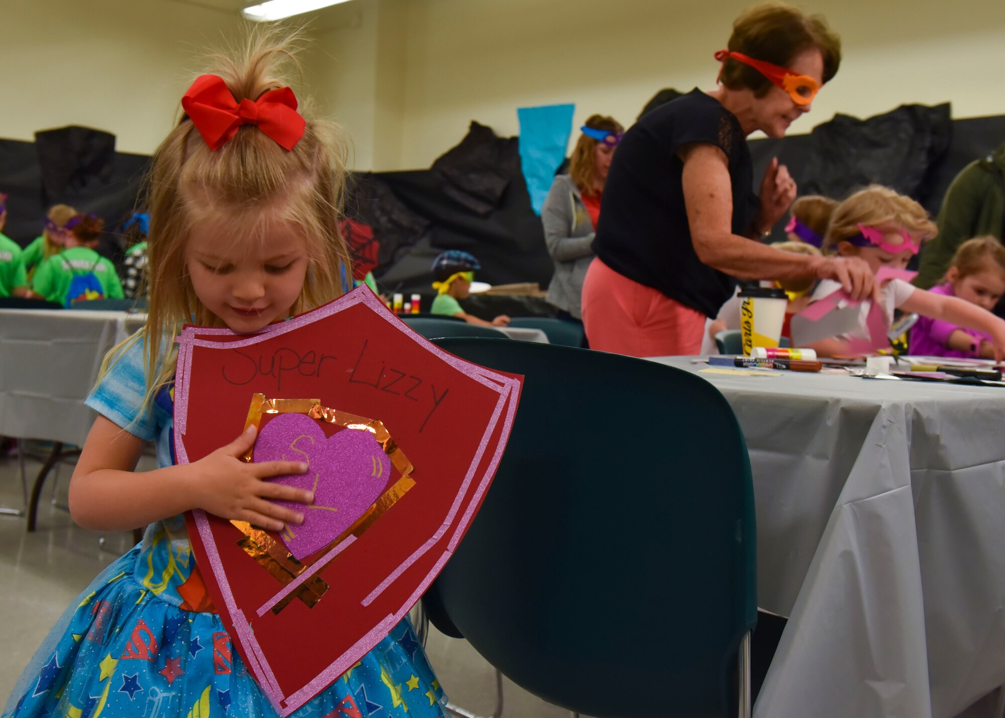 A young girl holds up a shield that her mother created for her