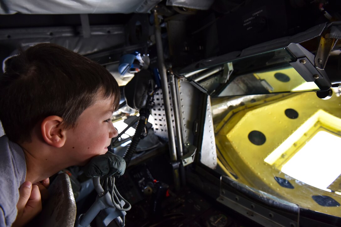 A boy lays in the boom operators pod and looks out of the boom pod’s window