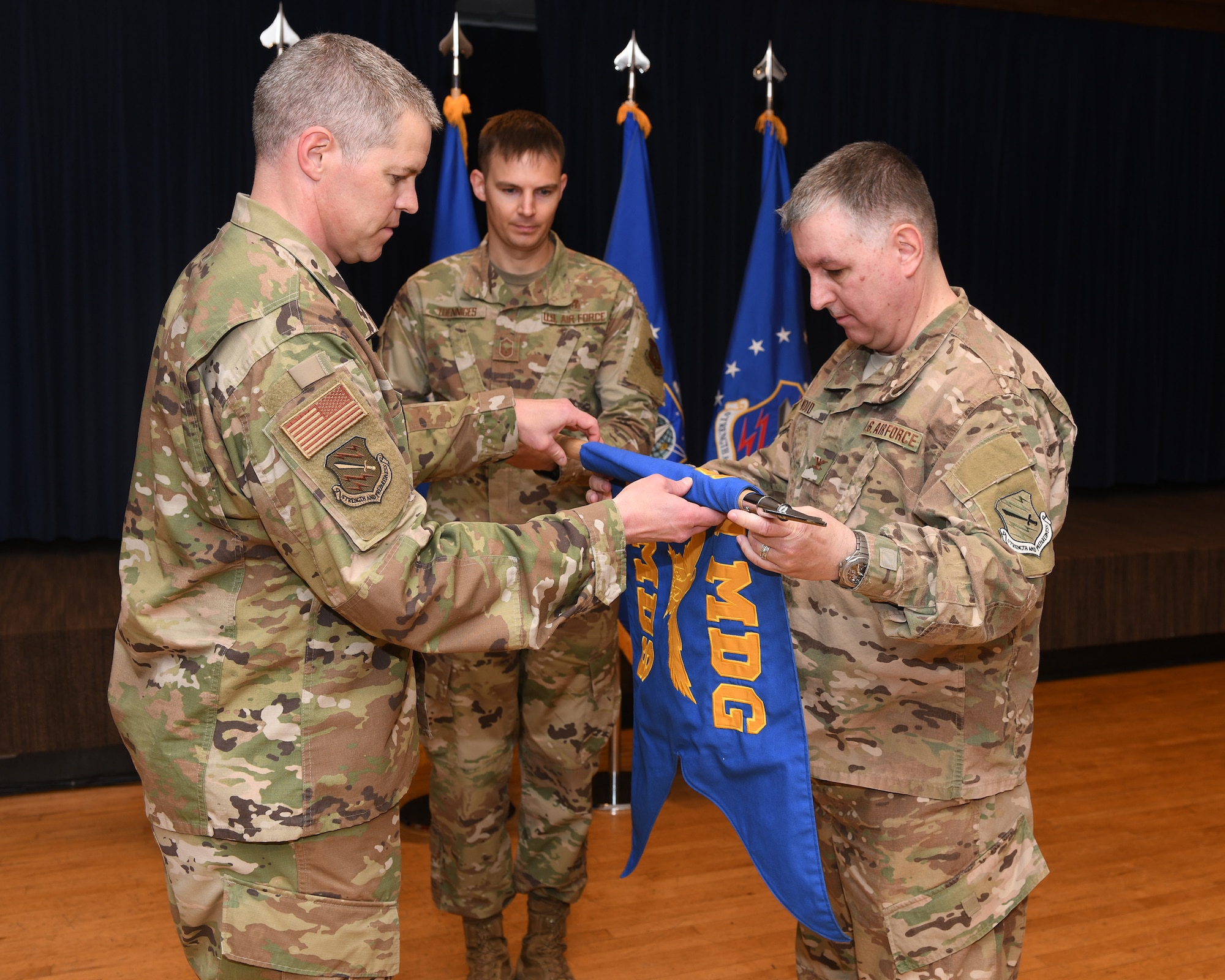 Col. Sam Johnson, 21st Space Wing vice commander, left, and Col. Michael J. Wood, the 21st Aerospace Medicine Squadron commander, roll up the 21st AMDS guidon July 19, 2019, on Peterson Air Force Base, Colorado. The 21st AMDS was redesignated as part of the 21st Operational Medical Readiness Squadron. (U.S. Air Force photo by Airman 1st Class Andrew Bertain)
