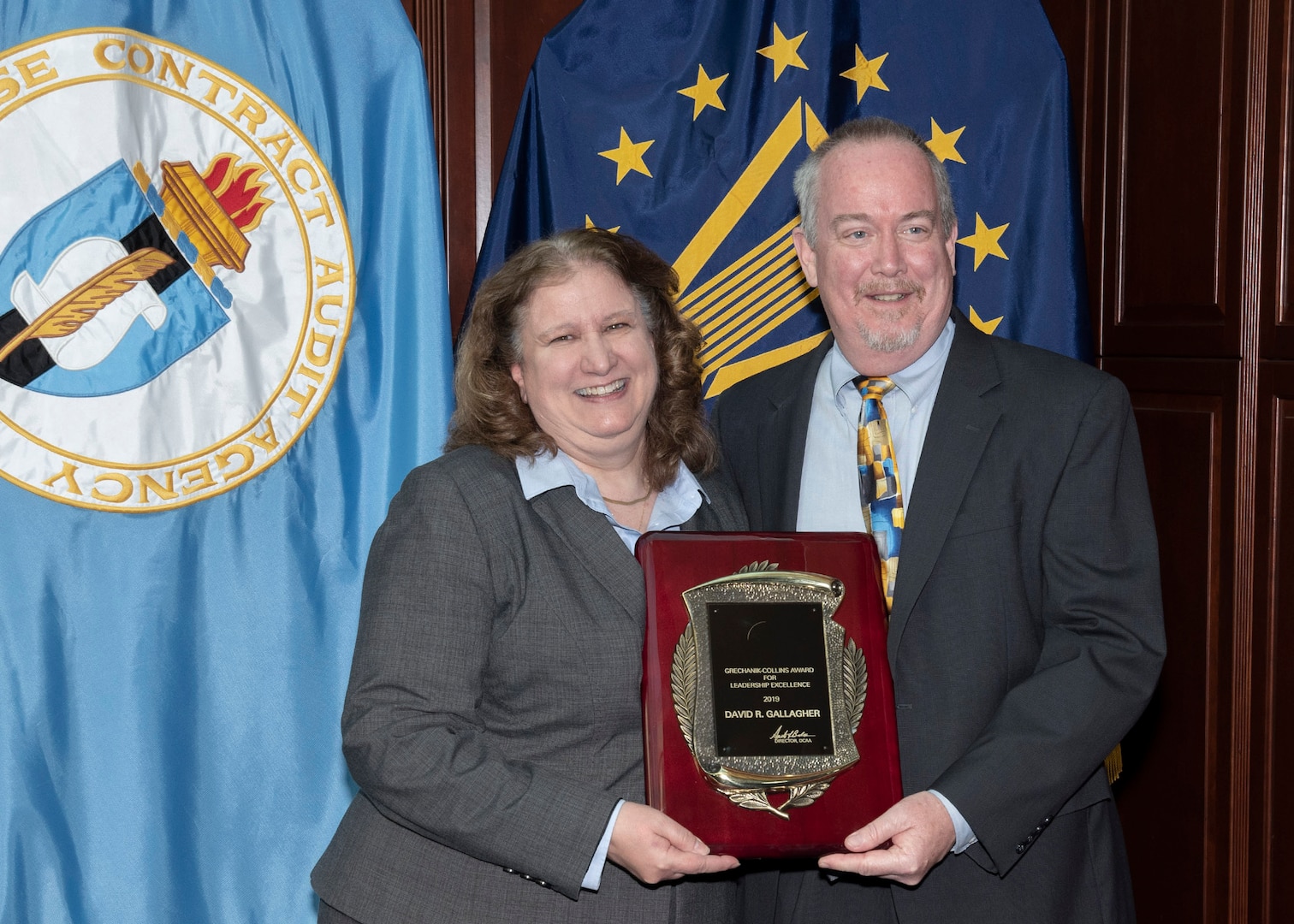 two individuals pose with award