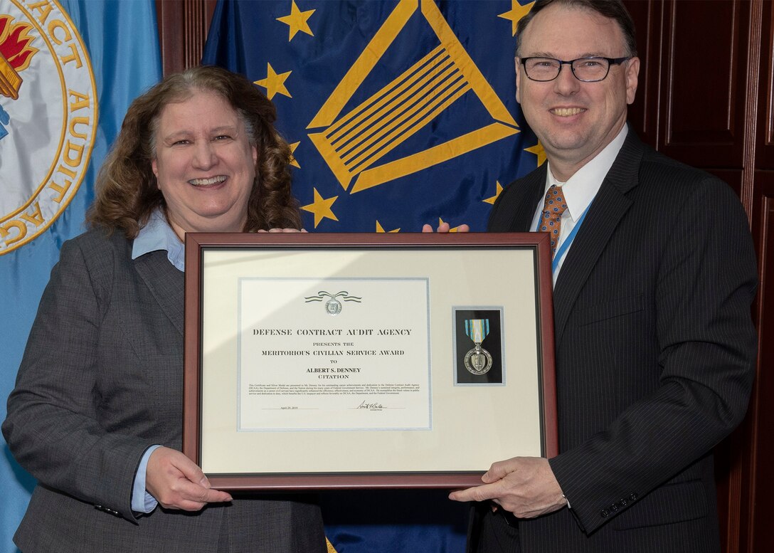 two individuals pose with award