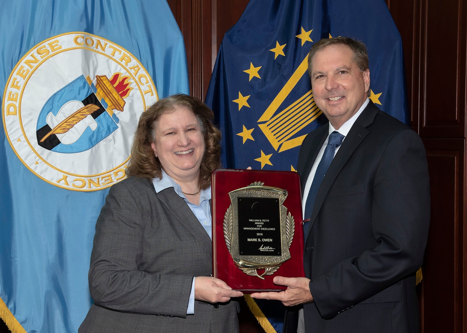 two individuals pose with award