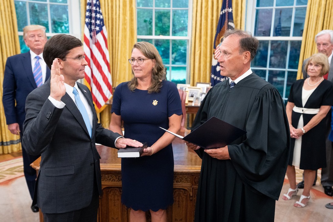 Dr. Mark T. Esper raises his right hand and lays his left on a book while standing before a judge.