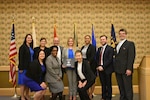 nine individuals pose with graduation diplomas