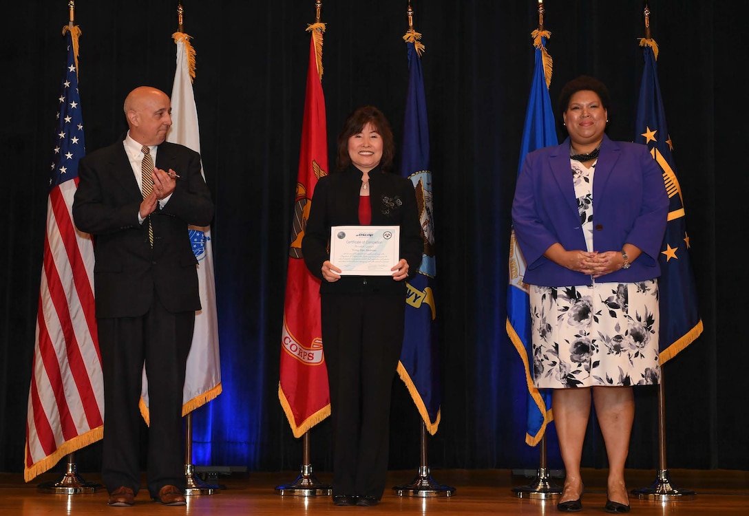 three individuals pose during graduation ceremony