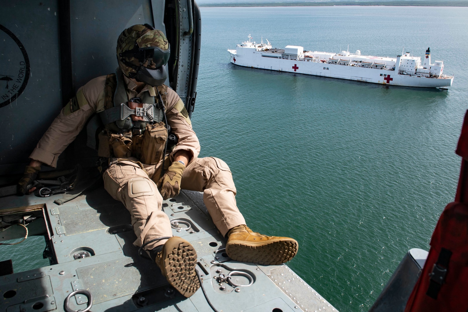 A Sailor looks out from a helicopter.