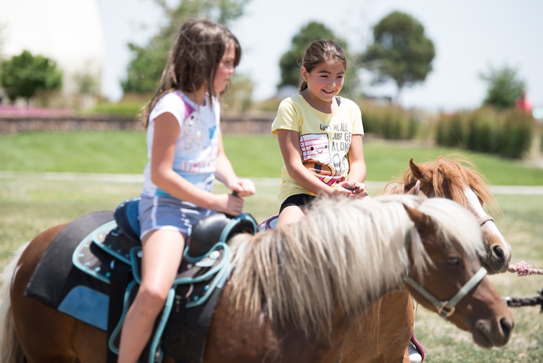 Kendra, 7, left, and Serenity, 10, ride ponies during the Summer Slam base picnic at Schriever Air Force Base, Colorado, July 19, 2019. The Summer Slam is held every year during summer to give Schriever Airmen an opportunity to meet, enjoy some time away from their duties while enjoying games and refreshments. (U.S. Air Force photo by 2nd Lt. Idalí Beltré Acevedo)