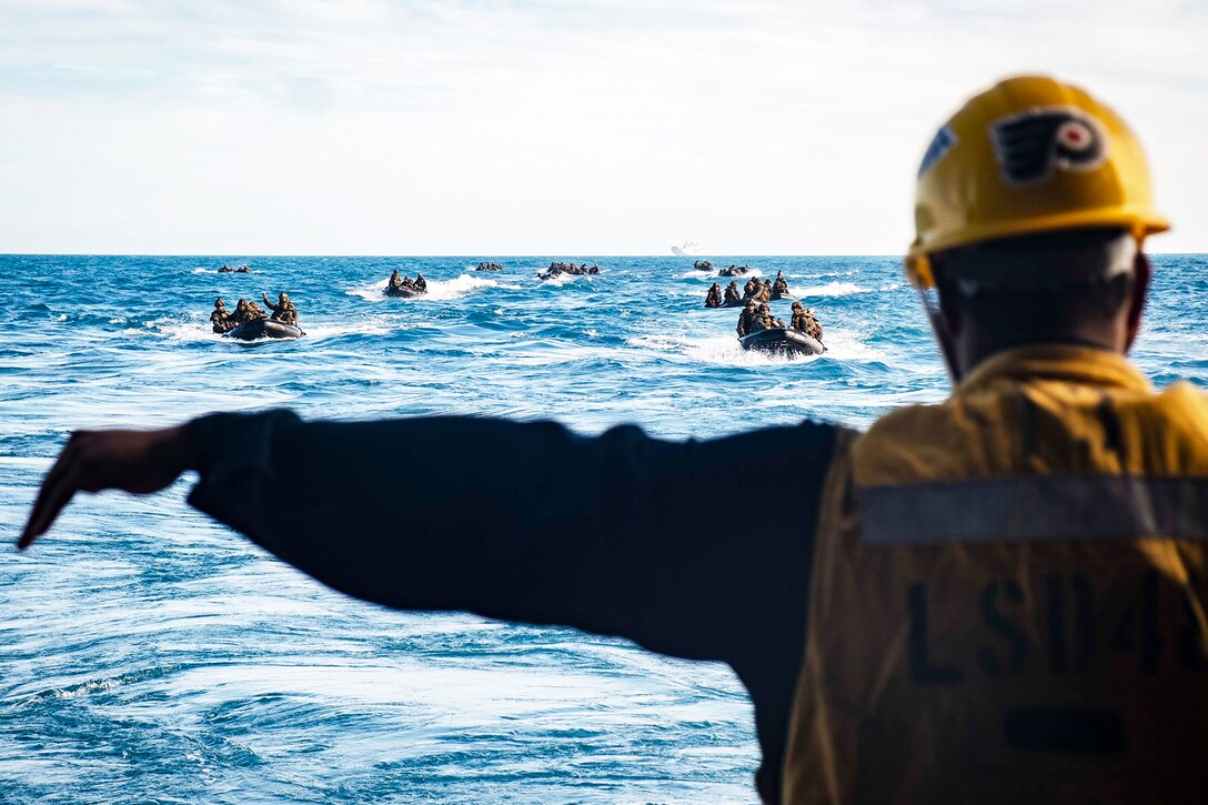 A man signals to Marines in the ocean.