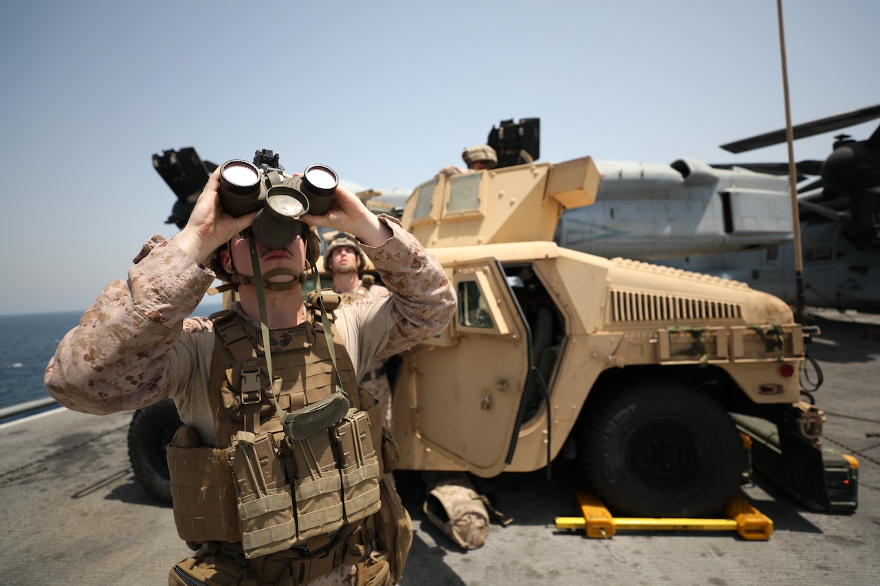 Marine looks skyward through binoculars.