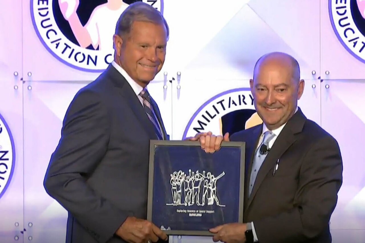 Two men stand holding a plaque