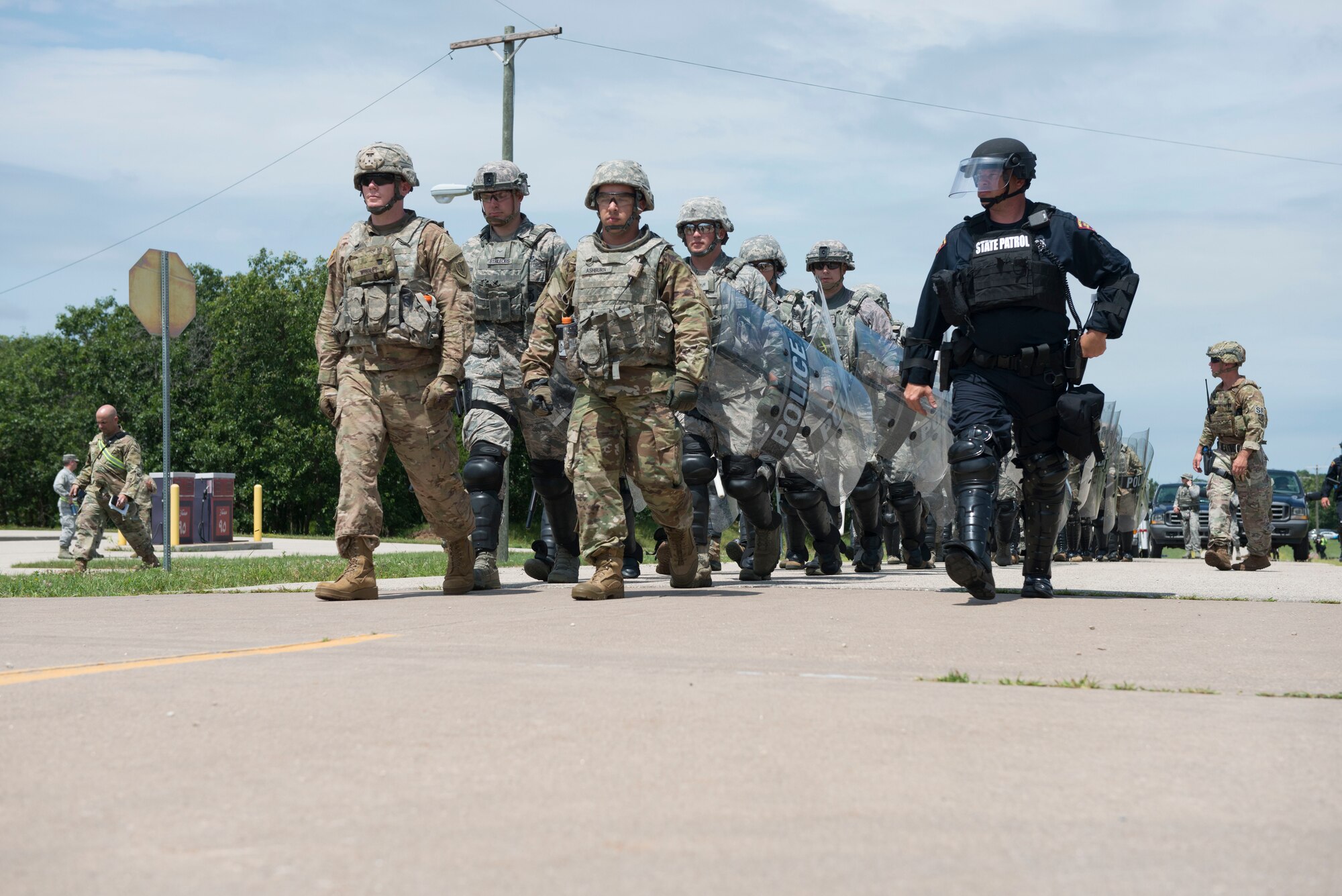 National Guardsmen assigned to the New Hampshire Army National Guard and the New Hampshire and Connecticut  Air National Guard march in formation with members of the Wisconsin State Patrol in a riot-control scenario during the PATRIOT North 19 domestic operations exercise, July 18, 2019 at Fort McCoy, WI. PATRIOT North is an annual domestic operations exercise, which tests the ability of the National Guard to work together with local, state and federal entities to respond to emergencies. (U.S. Air National Guard photo by Tech. Sgt. Tamara R. Dabney