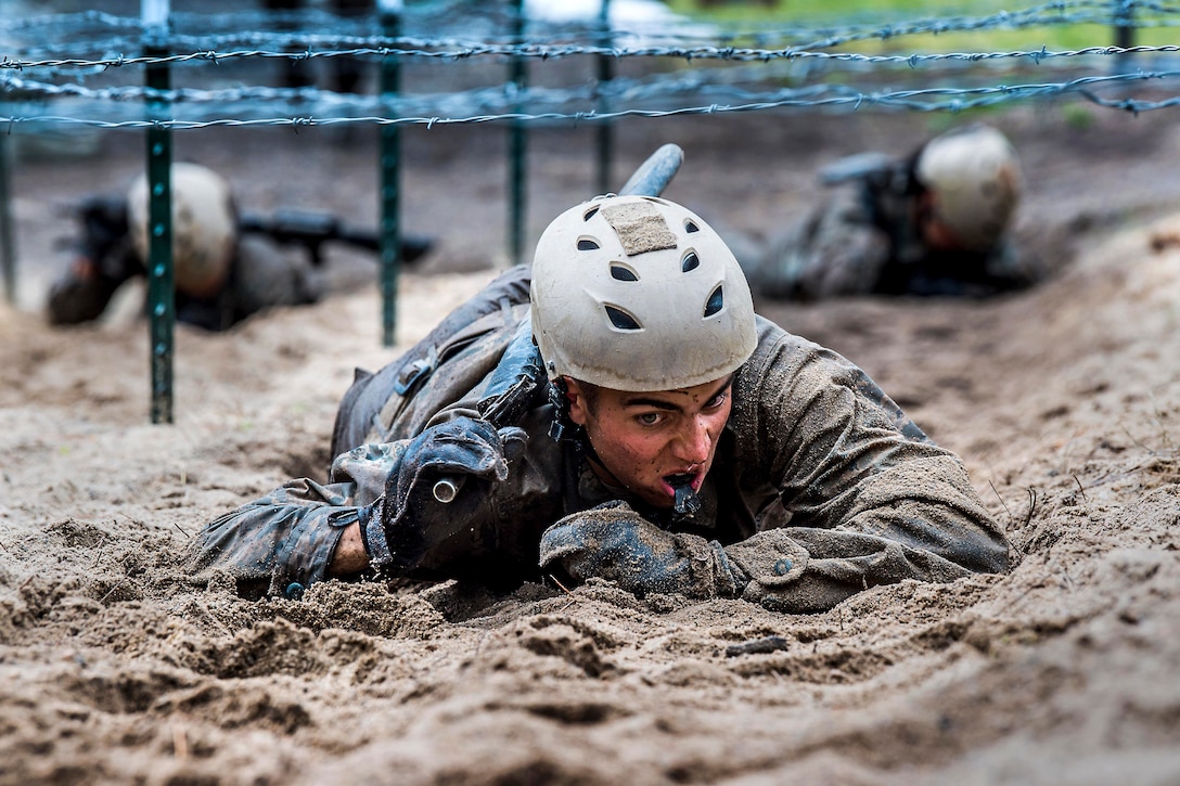 A cadet crawls under barbed wire.