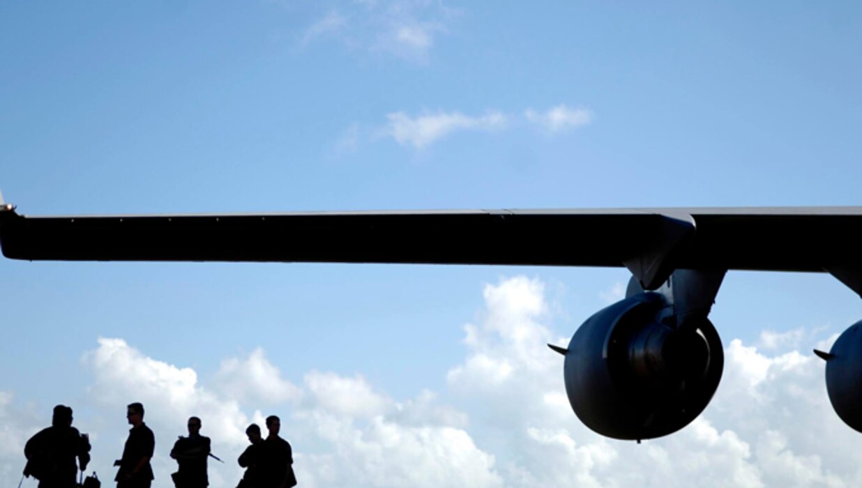 Airmen in silhouette under a plane