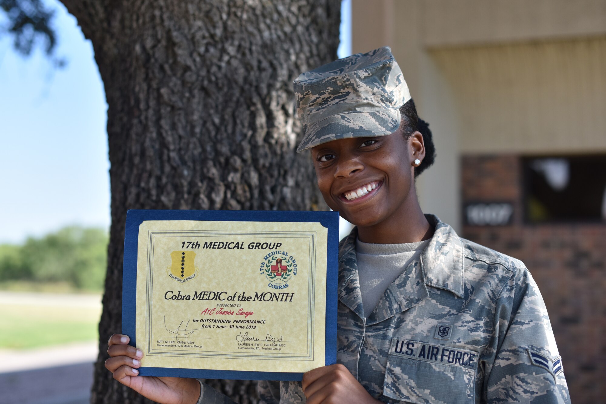 U.S. Air Force Airman 1st Class Jessica Savage, 17th Medical Support Squadron referrals management clerk, stands under a tree outside the Ross Clinic on Goodfellow Air Force Base, Texas, July 15, 2019. Savage was selected by her supervisors and leadership as the June Medic of the Month due to her exceeding their standards of professionalism. (U.S. Air Force photo by Senior Airman Seraiah Wolf/Released)