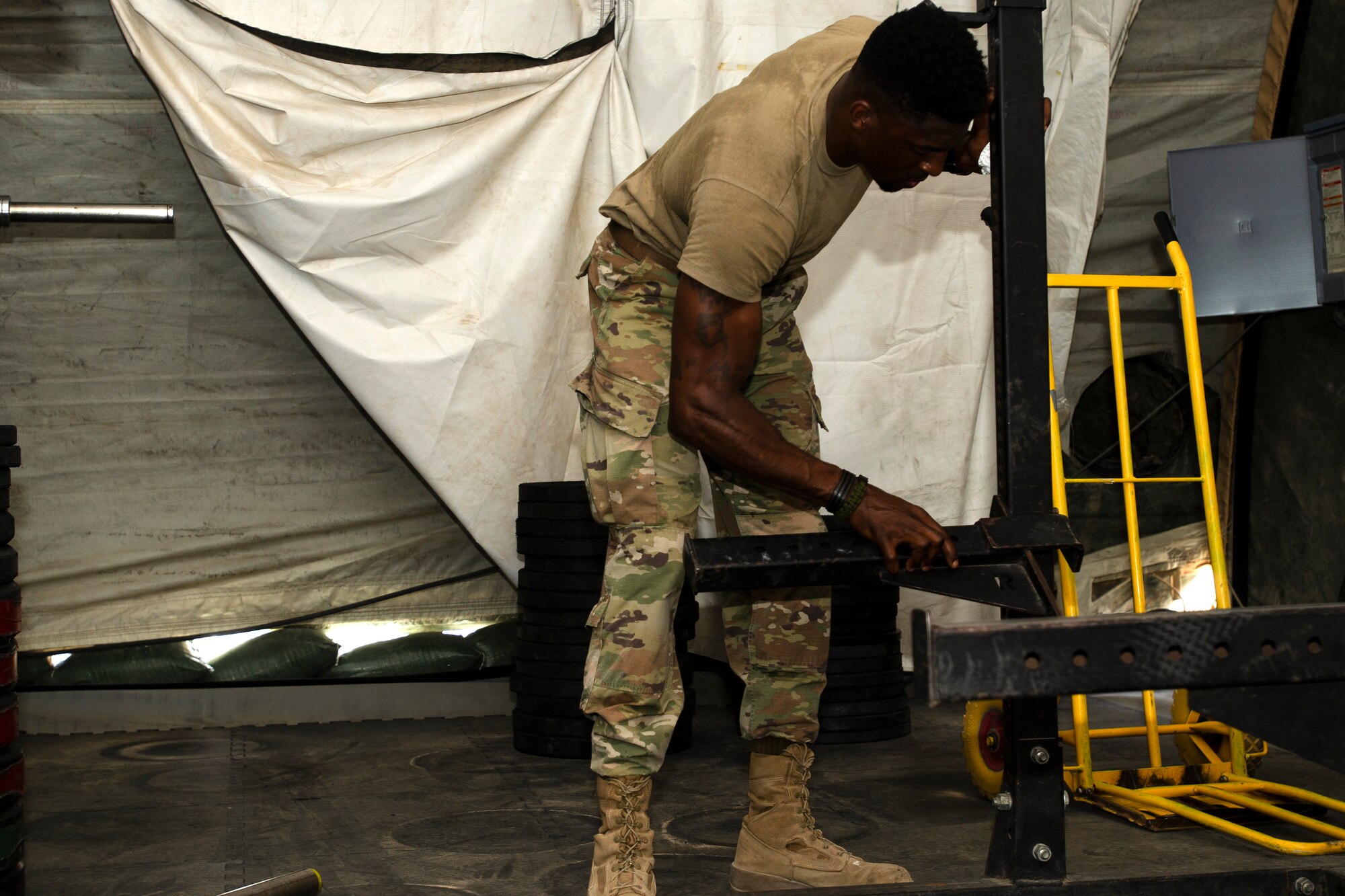 U.S. Air Force Master Sgt. Alonza Loury, 386th Expeditionary Force Support Squadron, moves workout equipment in the new fitness tent on Ali Al Salem Air Base, Kuwait, July 24, 2019. The new fitness tent is slated to open Aug.1, 2019, replacing the original facility which is scheduled for demolition to make room for future base improvement projects. This facility offers Airmen a second fitness location and expected to be in use until mid-November when the more permanent structure is completed. (U.S. Air Force photo by Capt. Stephen Hudson)