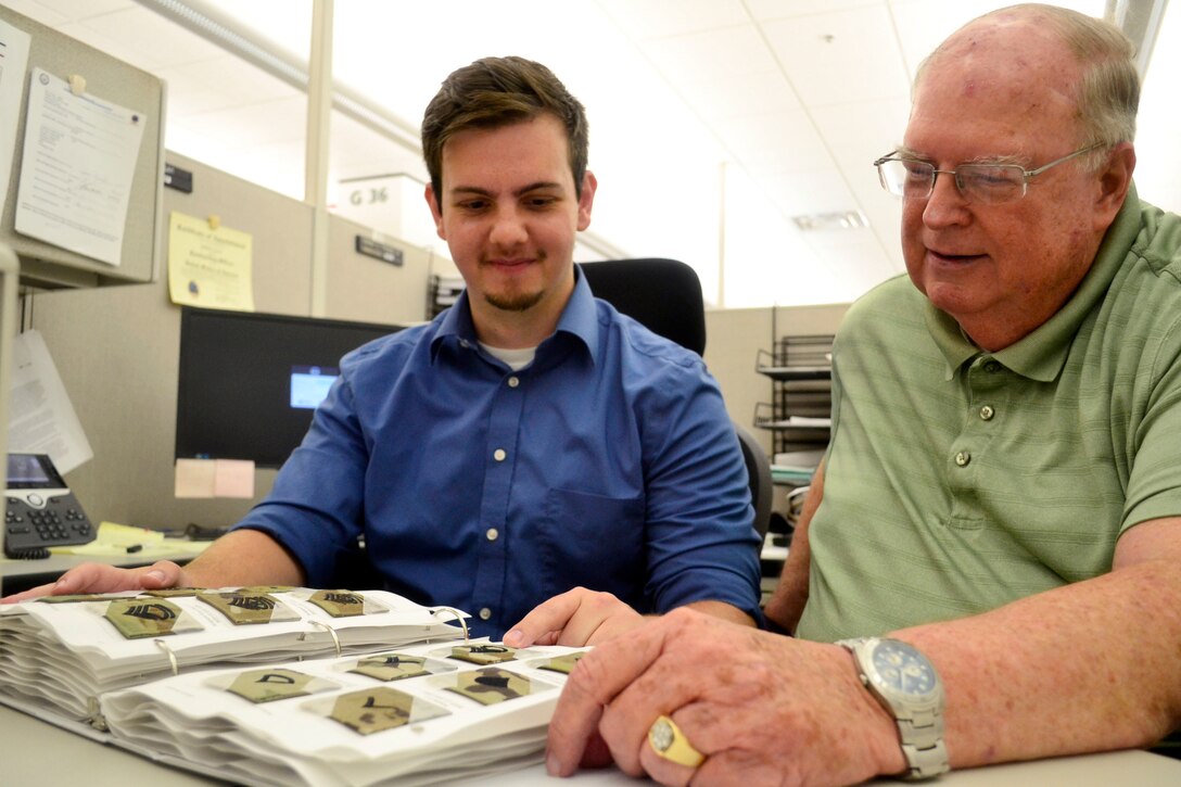 DLA Troop Support Clothing and Textiles contracting officers Robert Fagan, left, and Stanley C. Thomas Jr., review U.S. Army rank insignia and service tape