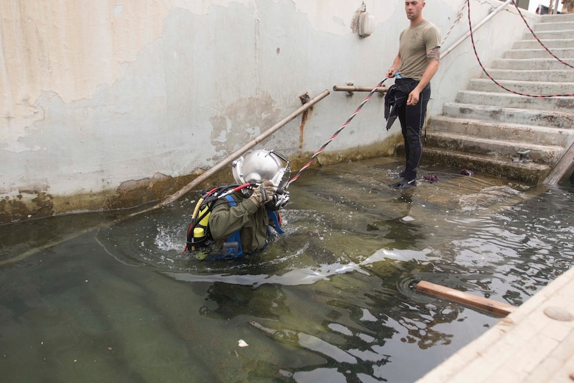 Army Sgt. Michael Pate, diving supervisor, 511th Engineer Dive Detachment, stands as a safety to Army diver, Pfc. Richard Ratliff, 511th Engineer Dive Detachment, during their annual training event ‘shallow brown’ at Kuwait Naval Base, Kuwait, July 19, 2019. The detachment is deployed to Kuwait in support of Operation Spartan Shield for U.S. Army Central. This training ensures the readiness of Soldiers within the ranks through equipment checks and qualifications.