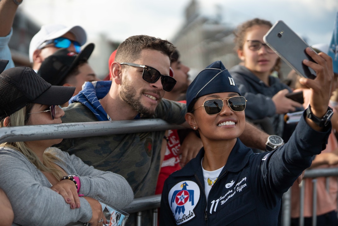 An airman takes a selfie with spectators.