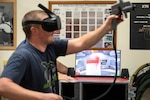 Travis McGreger, Shop 71, Painters, Blasters and Tilesetters, training instructor, demonstrates how the virtual reality paint sprayer trainer works July 10, 2019, in a Continuous Training and Development classroom in Building 460.