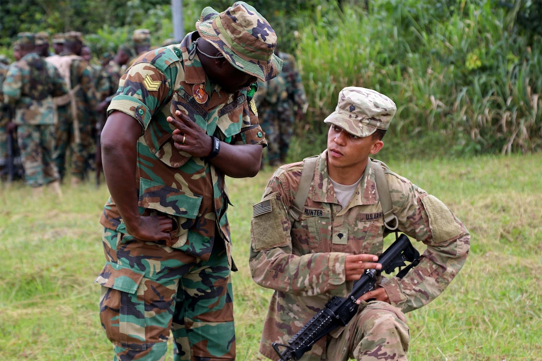 A soldier from Ghana and a U.S. soldier, both in camouflage uniforms, talk while training together.