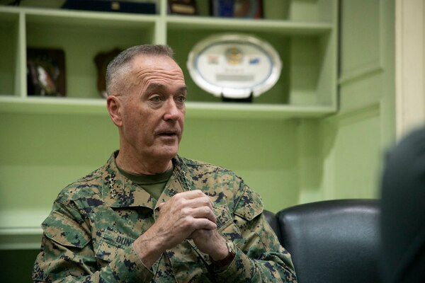 Four-star Marine Corps general listens to a question while seated at a conference table.