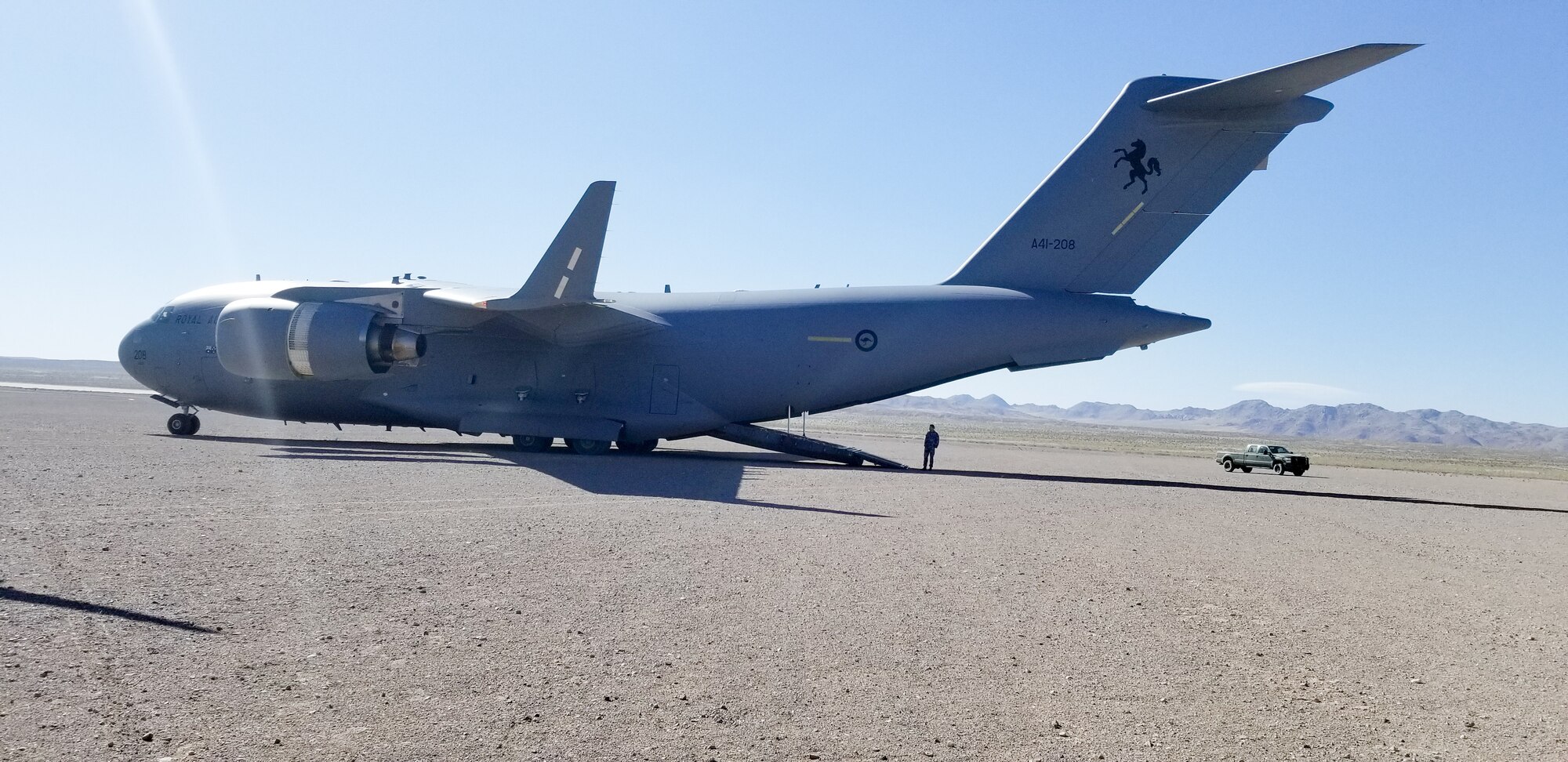 Maj. Dennis Martin, 225th Air Defense Squadron air battle manager, watches as a Royal Australian Air Force C-17 lands on the dirt strip at Bicycle Lake Army Air Field near Fort Irwin, California, as part of Exercise Rainier War June 26, 2019.  Martin is one of four air battle managers flying onboard the C-17s during the exercise in order to accomplish a portion of his training requirements to convert to a rated air battle manager.  (Courtesy Photo by Maj. Dennis Martin)