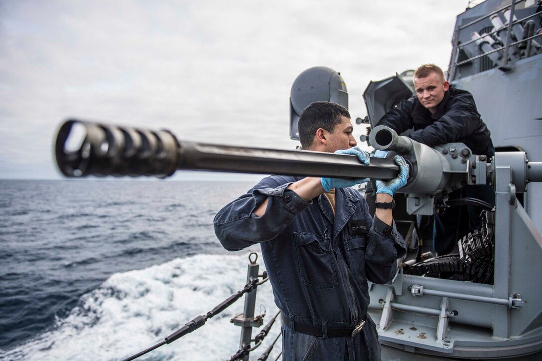 Fire controlman (left) and gunner’s mate maintain Mark 38 25mm machine gun aboard USS Porter in Atlantic Ocean, March 5, 2019 (U.S. Navy/James R. Turner)