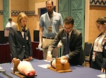 Uniformed Services University's Dr. Craig Goolsby (center) observes as high school students at a conference in Orlando, Florida, practice using a tourniquet after watching a web-based tutorial. Goolsby is researching effective teaching methods as part of a grant to develop a trauma first-aid course for students that incorporates elements of Stop the Bleed.