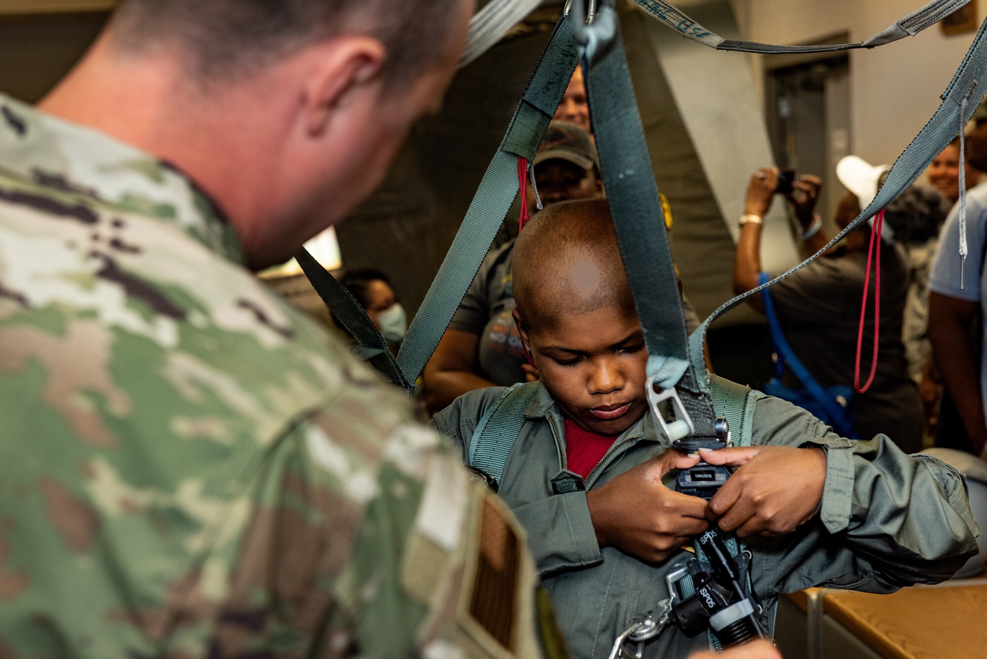 Tech. Sgt. Christopher Lineberry, quality assurance, 509th Operations Support Squadron, assists Emil “Batman” Conley from Lee Summit, Missouri, with putting on an egress system harness during the Pilot for a Day tour on July 19, 2019, at Whiteman Air Force Base, Missouri. Aircrew flight equipment specialists perform maintenance and coordination of seats, hatches, canopies and modules, to ensure that pilots can make a safe escape in case of emergency. Emil has medulloblastoma, which is the most common malignant brain tumor for children, and accounts for about 20 percent of all childhood brain tumors. Whiteman AFB collaborates with St. Jude Children’s Research Hospital to coordinate these tours. (U.S. Air Force photo by Senior Airman Thomas Barley)
