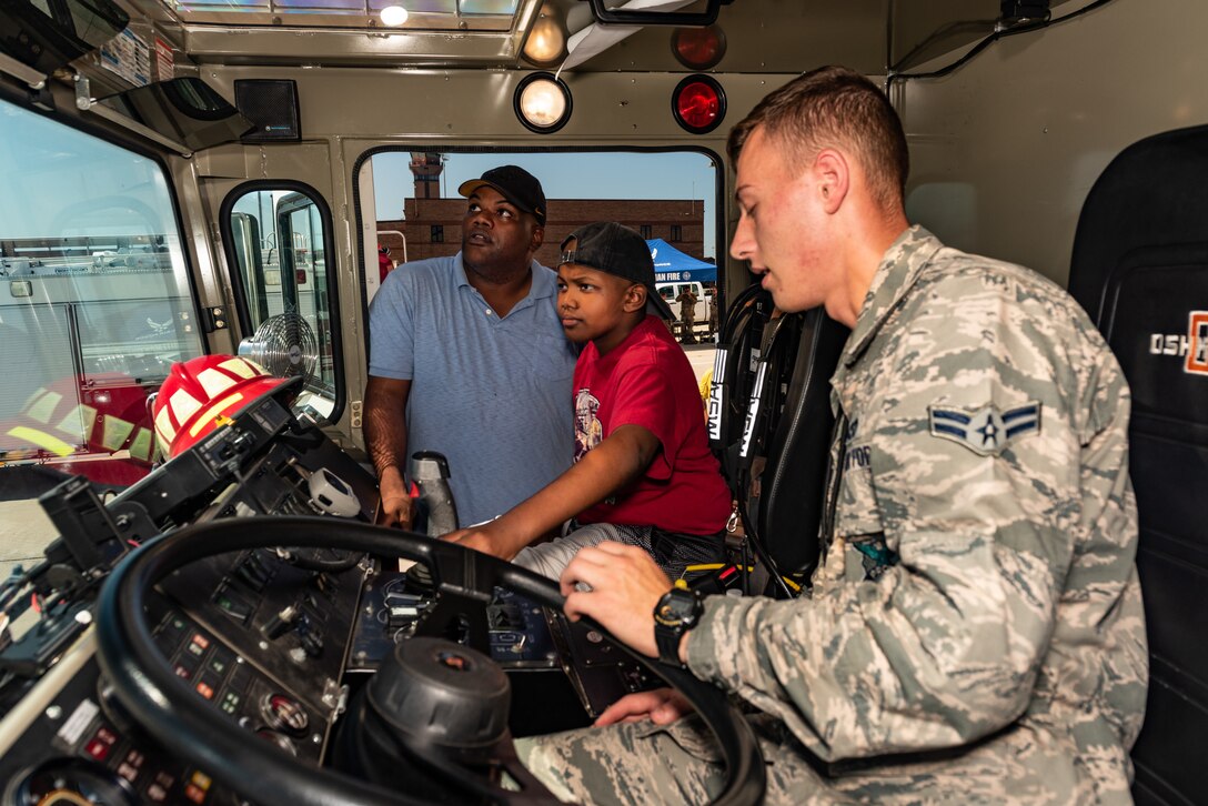 Airman 1st Class Henry Schuermann, Firefighter, 509th Civil Engineer Squadron, teaches Emil “Batman” Conley and his father Marcus from Lee Summit, Missouri, how to shoot water out of a fire truck during the Pilot for a Day tour on July 19, 2019, at Whiteman Air Force Base, Missouri. Emil received a flight suit along with a patch with his call sign “Batman” the day prior at a pool party hosted by the 393rd Bomb Squadron. Emil has medulloblastoma, which is the most common malignant brain tumor for children, and accounts for about 20 percent of all childhood brain tumors. Whiteman AFB collaborates with St. Jude Children’s Research Hospital to coordinate these tours. (U.S. Air Force photo by Senior Airman Thomas Barley)