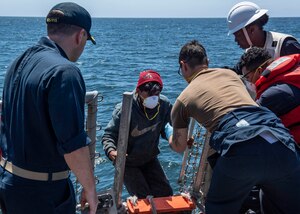 A man boards a ship via a ladder.