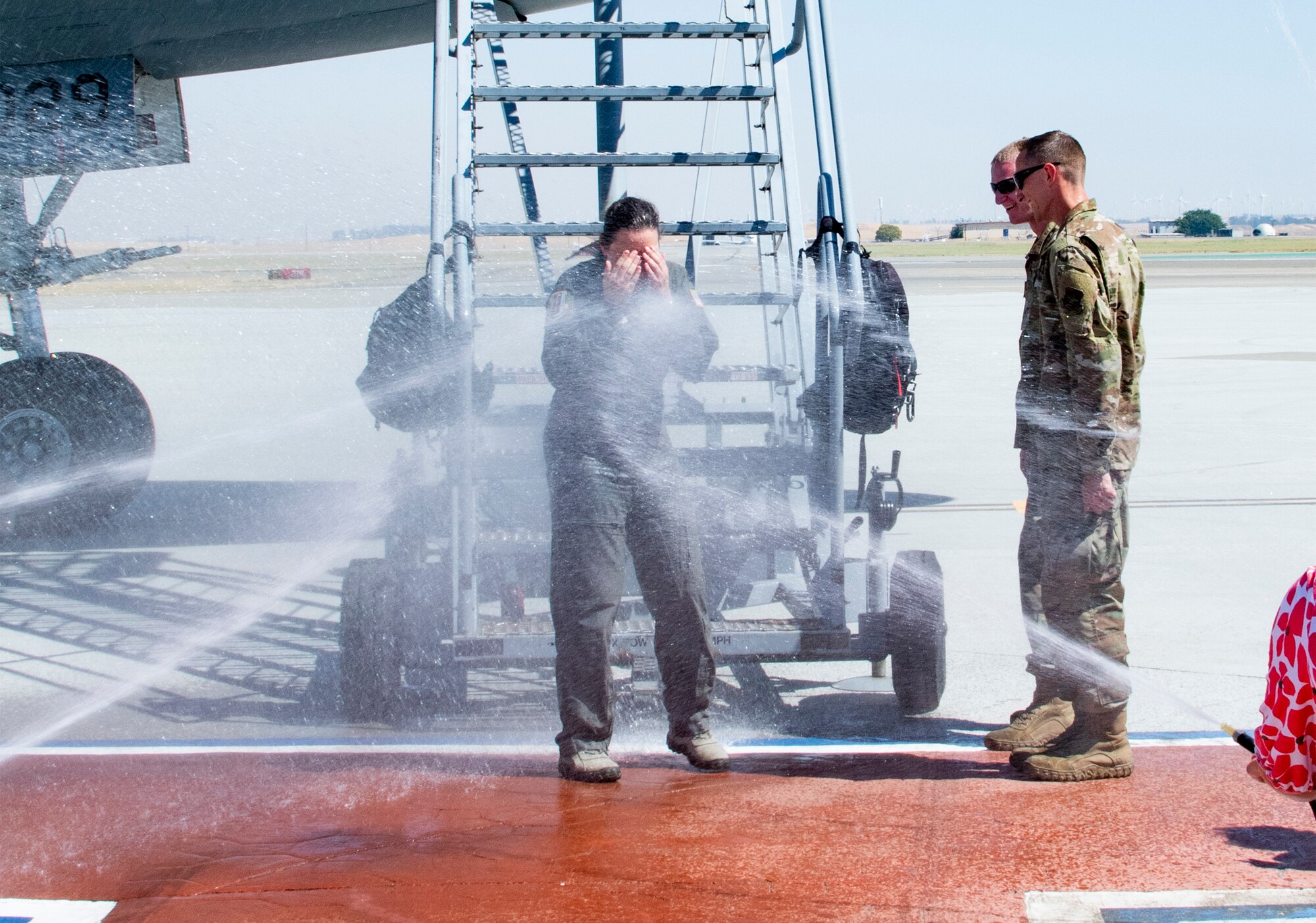 U.S. Air Force Col. Theresa Weems, 60th Operations Group commander, gets doused after her final flight at Travis Air Force Base, California, July 24, 2019. Fini-flights are a traditional way to mark milestones in the career of aircrew, respected individuals of rank or repute, or a commander's departure to another command. Weems has served as the commander for the 60th OG for the largest air mobility wing in the Air Force since July 2017. (U.S. Air Force photo by Heide Couch)