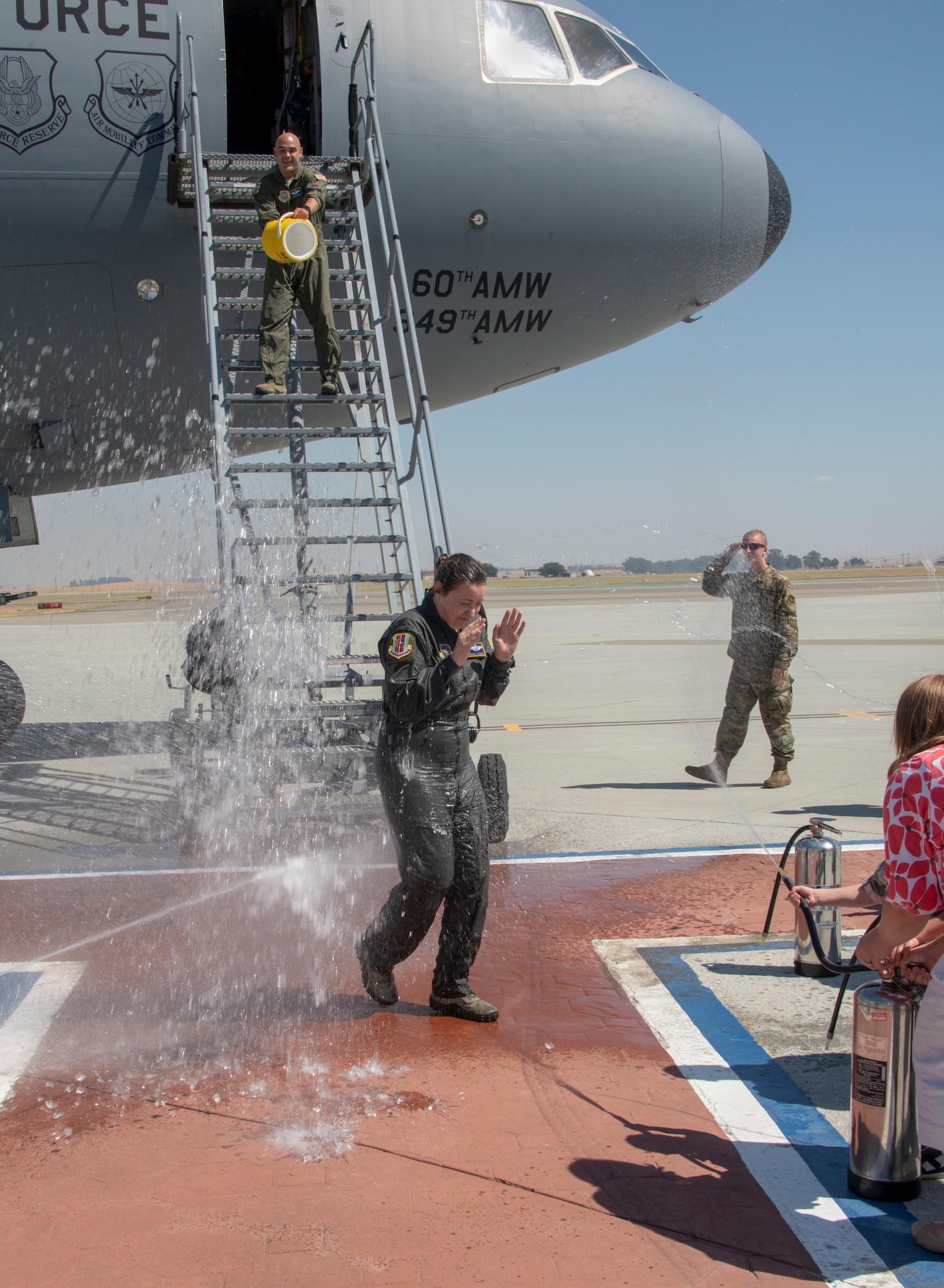 U.S. Air Force Col. Theresa Weems, 60th Operations Group commander, gets doused after her final flight at Travis Air Force Base, California, July 24, 2019. Fini-flights are a traditional way to mark milestones in the career of aircrew, respected individuals of rank or repute, or a commander's departure to another command. Weems has served as the commander for the 60th OG for the largest air mobility wing in the Air Force since July 2017. (U.S. Air Force photo by Heide Couch)