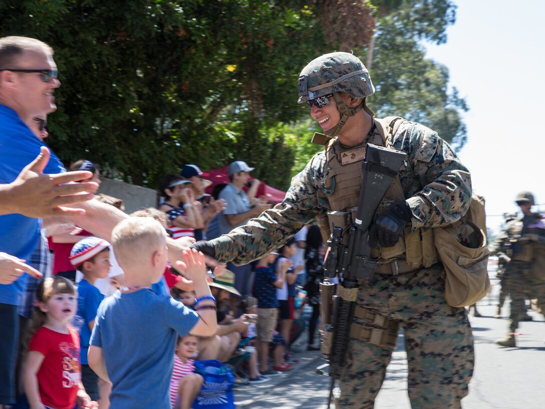 U.S. Marine Corps Lance Cpl. Adolfo Cartagena with 1st Law Enforcement Battalion, 1st Marine Expeditionary Force Information Group (I MIG) marched and greeted the locals during the Independence Day parade at Lake Forest, California, July 4, 2019. I MIG is committed to strengthening community ties through volunteering and supporting public engagement with a showing of Marines, color guard and tactical vehicles.(U.S. Marine Corp photo by Cpl. Anabel Abreu Rodriguez)