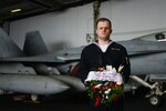 CORAL SEA (July 26, 2019) Religious Program Specialist 3rd Class Johnathan Groves stands with a ceremonial wreath in the hangar bay aboard the Navy’s forward-deployed aircraft carrier USS Ronald Reagan (CVN 76) prior to a remembrance ceremony for USS Lexington (CV 2). Ronald Reagan is the first aircraft carrier to commemorate Lexington since the discovery of the wreckage in 2018. Ronald Reagan, the flagship of Carrier Strike Group 5, provides a combat-ready force that protects and defends the collective maritime interests of its allies and partners in the Indo-Pacific region.