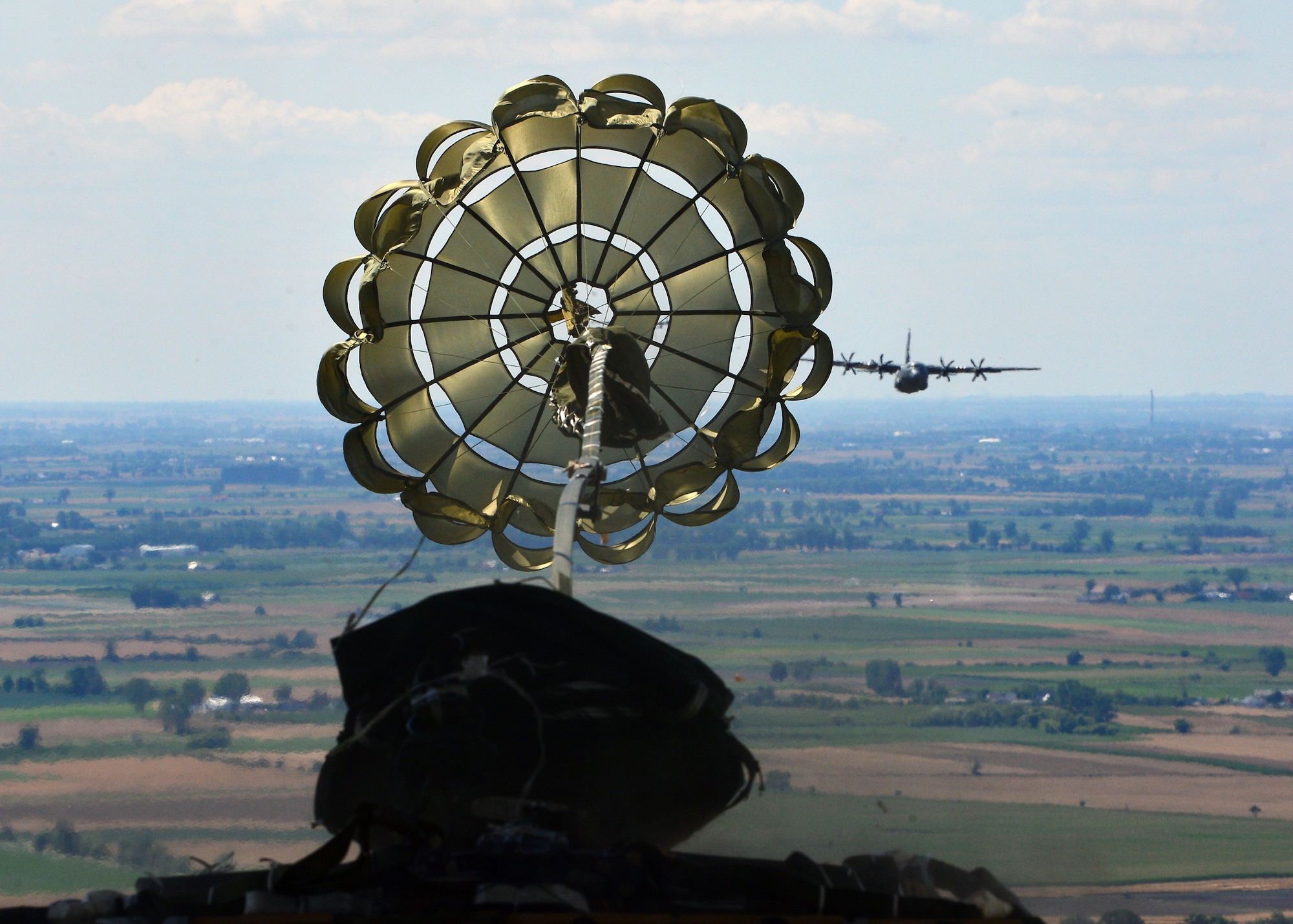 A parachute deploys from an airdrop platform during an Aviation Rotation 19-3 training flight over Powidz Air Base, Poland, July 18, 2019. Aircrew members performed low-cost low-altitude, container delivery system, and heavy equipment air drops to maintain operation proficiency. (U.S. Air Force photo by Staff Sgt. Jimmie D. Pike)
