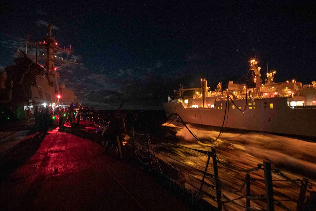 Two ships are seen on the ocean at night.