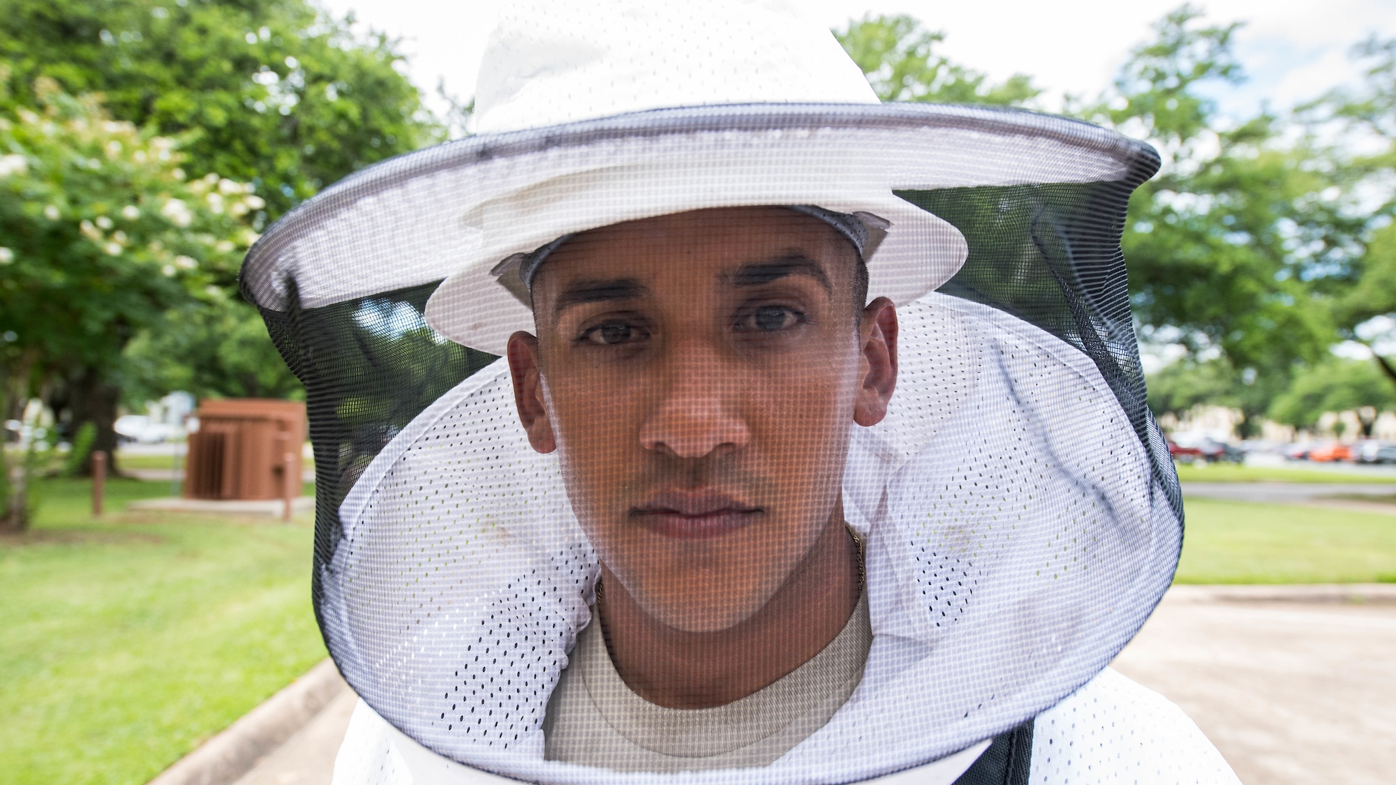 Airman 1st Class Alberto Montesino, a 2nd Civil Engineer Squadron pest management apprentice, wears a bee suit after dealing with a colony of bees at the 2nd Bomb Wing Headquarters Building at Barksdale Air Force Base, Louisiana, June 6, 2019.  The 2nd CES pest management shop relocates bees by capturing the queen bee and taking her to a new location where the rest of the colony will follow. (U.S. Air Force photo by Airman Jacob B. Wrightsman)