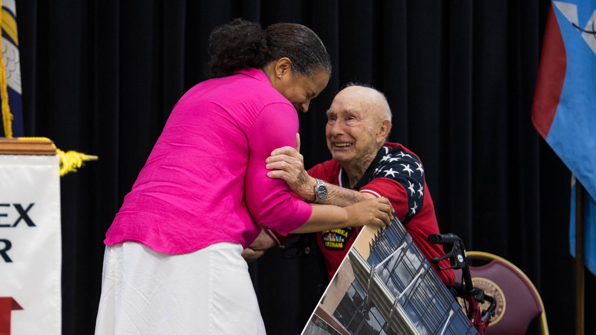 Col. Sara A. Custer (left), 2nd Mission Support Group commander, announces to  retired Col. Steven L. dePyssler (right), 2nd MSG retiree affairs director, and the attendees of his 100th birthday celebration that the 2nd MSG  building is  renamed after dePyssler at the Bossier Civic Center, Bossier City, Louisiana, July 19, 2019.  The building will now be called the dePyssler Mission Support Group Building.  (U.S. Air Force photo by Airman Jacob B. Wrightsman)