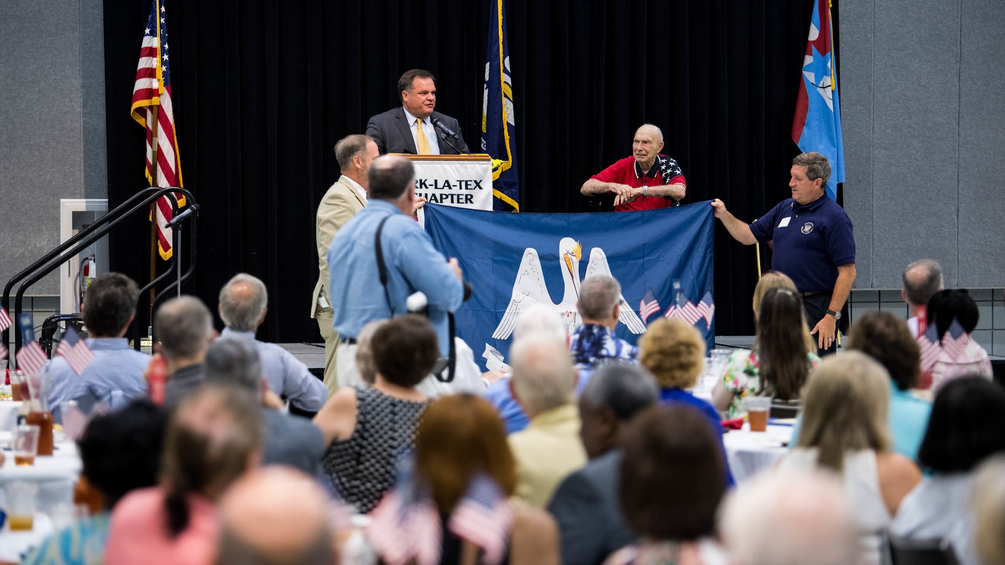 Louisiana State Senator Ryan Gatti (left), presents retired Col. Steven L. dePyssler (right) 2nd Mission Support Group retiree affairs director, with a Louisiana state flag that was flown at the Louisiana State Capitol Building during dePyssler's 100th birthday celebration at the Bossier Civic Center, Bossier City, Louisiana, July 19, 2019. dePyssler served in four different wars during his 38 years of active duty service. (U.S. Air Force photo by Airman Jacob B. Wrightsman)
