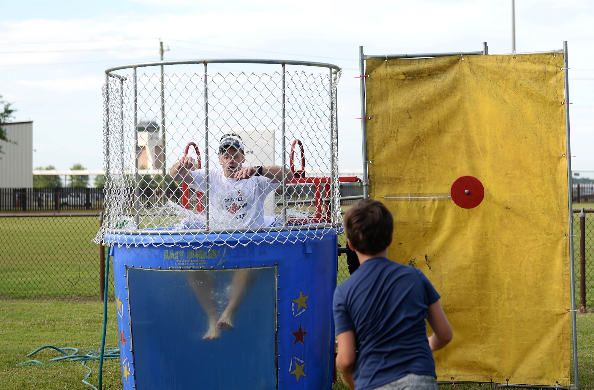 Col. William Denham, 14th Flying Training Wing vice commander, falls into a tank of water during BLAZE Fest July 3, 2018, on Columbus Air Force Base, Miss. Following the Eagles versus the Chiefs kickball game, attendees were able to throw balls at a target to try and dunk wing leadership throughout the evening. (U.S. Air Force photo by Airman 1st Class Hannah Bean)