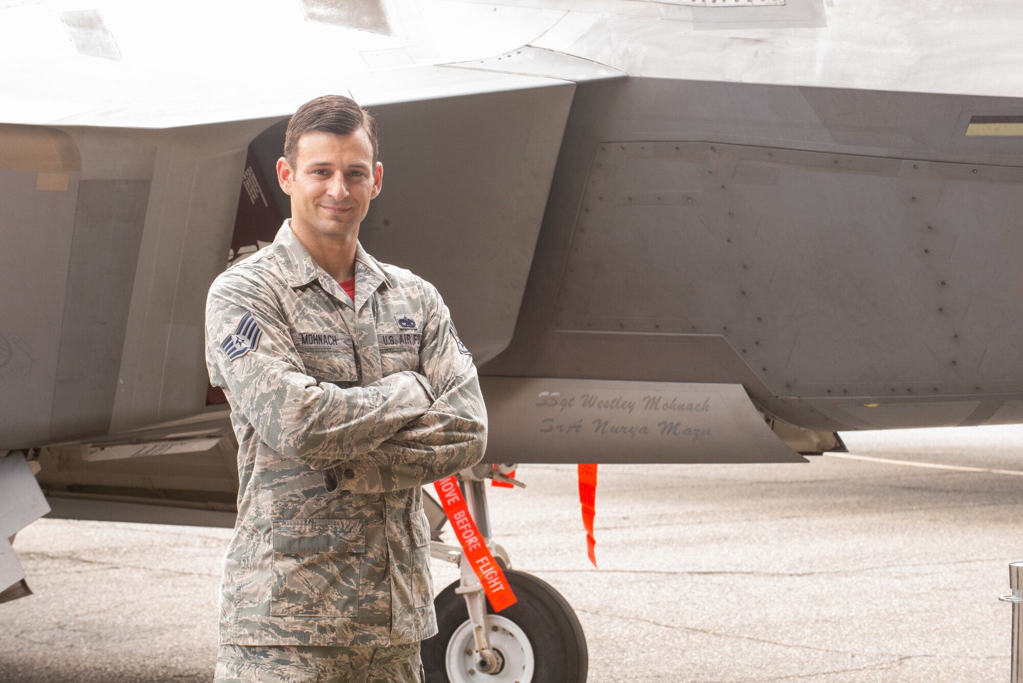 Dedicated crew chief Airman standing in front of an F-22 Raptor