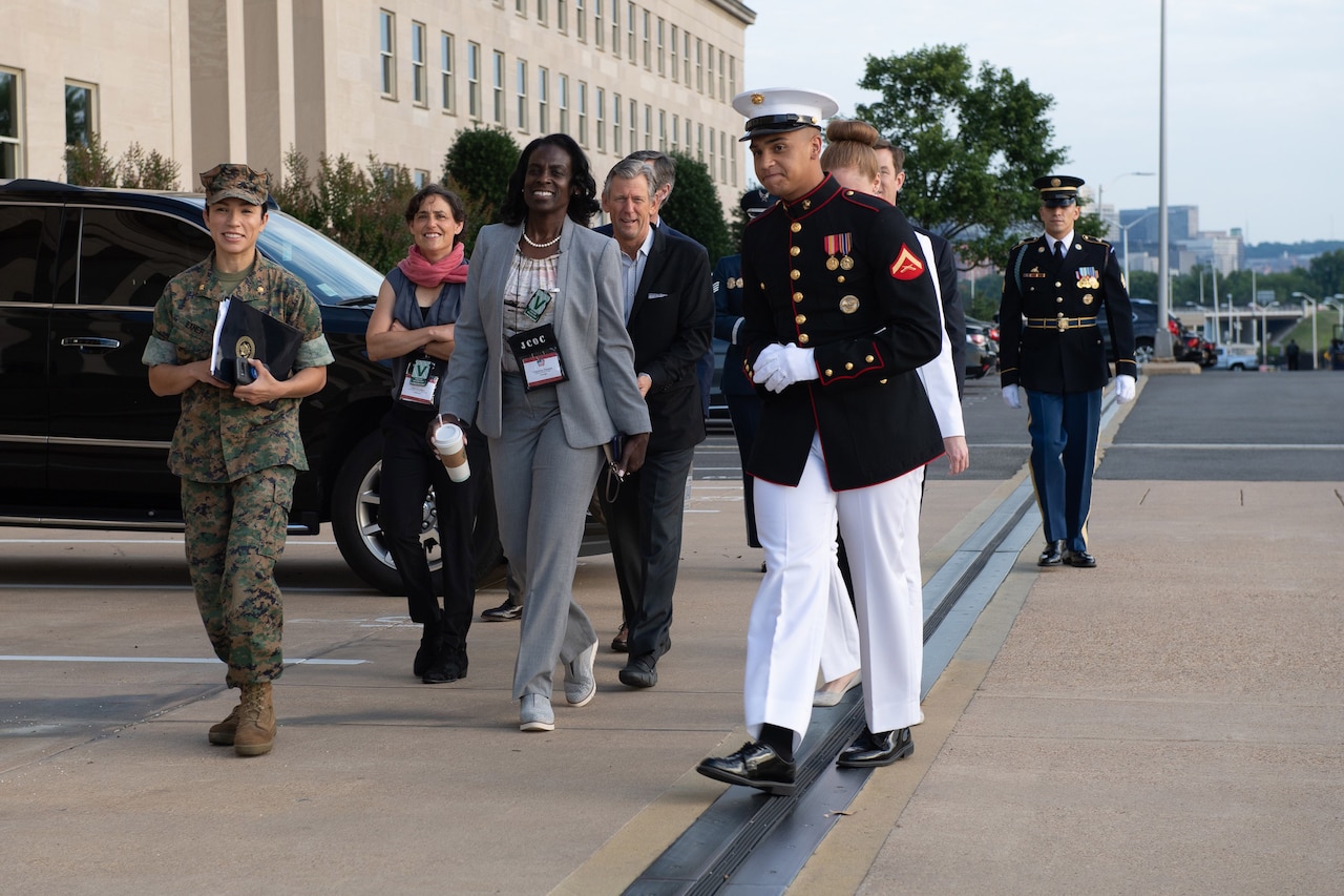 Service members walk with civilians outside the Pentagon.