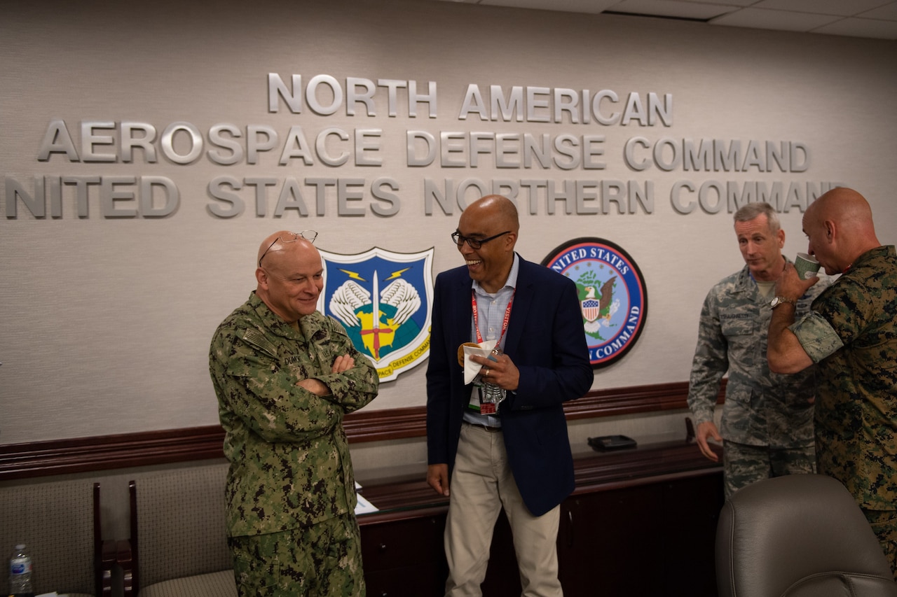 A civilian talks with a service member as others stand nearby.