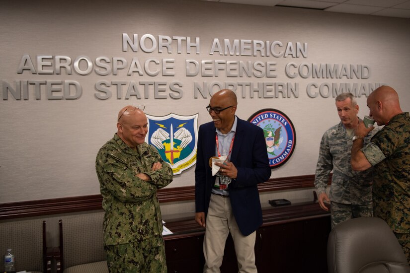 A civilian talks with a service member as others stand nearby.