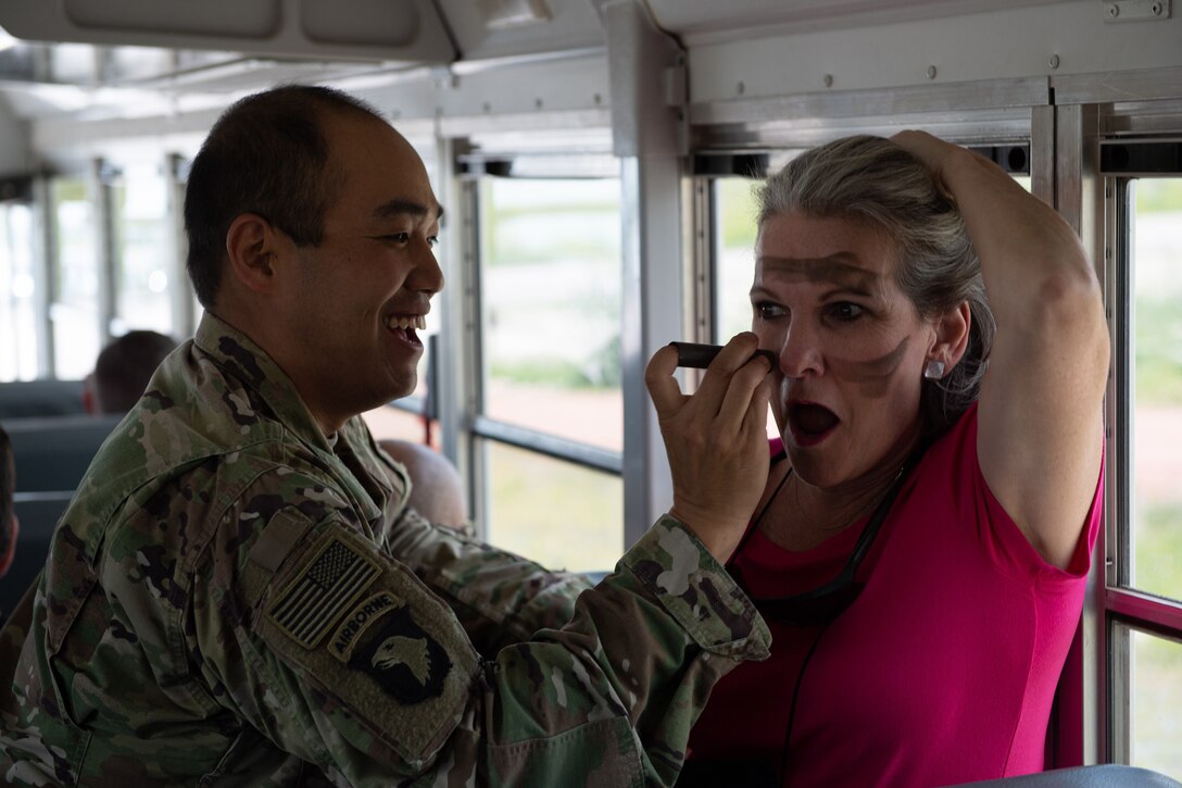 A soldier paints a civilian's face.